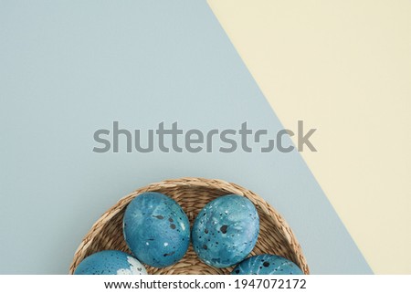 Stylish Easter background with creatively painted Easter eggs in a blue night sky in a wicker basket on a two-tone pastel background with space for text. Easter concept. Postcards, background