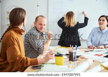 Designers waiting for the colleague to finish drawing on the board