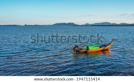 Single longtail boat of a local community anchored in the water surrounded by beautiful tropical natural environment of south of Thailand. 