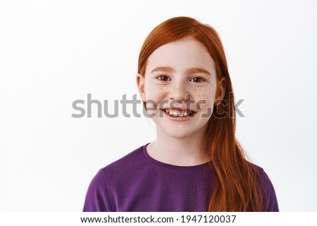Close up portrait of beautiful red haired girl with freckles, smiling with teeth and looking happy at camera, positive emotion, joyful kid, white background