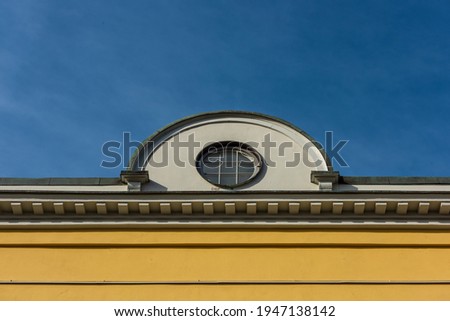 Small round roof window on a yellow building