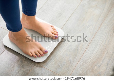 Close-up photo of woman legs stepping on floor scales indoors, space for text. Overweight problem Royalty-Free Stock Photo #1947168976