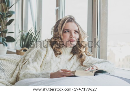 Cute young woman reading a book at home