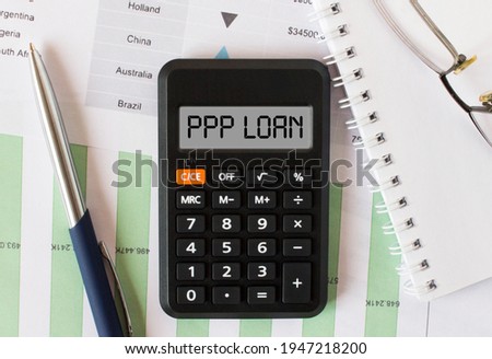 Calculator with the word PPP Loan on the display. Pen, eyeglasses and notepad on the diagrams. Concept photo