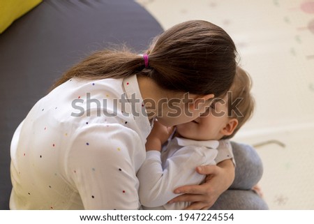 caucasian family little preschool baby boy and mom young woman hug joyfully together in living room at home with happiness smile. Child son congratulates on Mother's Day. Motherhood, childhood concept