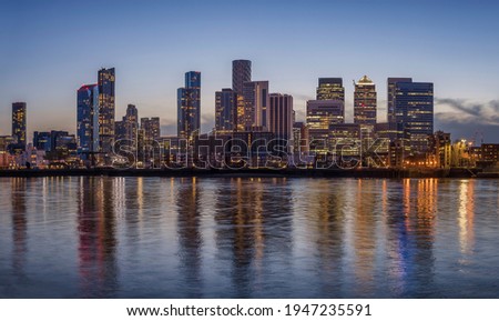 The financial district of London, Canary Wharf, with the illuminated, cooperate skysrcapers during evening time Royalty-Free Stock Photo #1947235591