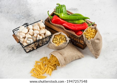 Mushrooms, chili peppers and pastas in rustic basket on white background