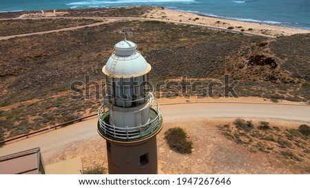 Aerial shot of high old historical lighthouse at a hill next to Indian Ocean near Exmouth, Western Australia
