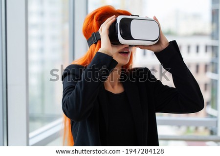 Young woman wearing virtual reality goggles in modern coworking studio.
