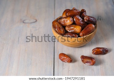 Closeup delicious Kurma Tunisia or sweet dried date palm fruits on wooden bowl. Much sought after during Ramadan to break the fast.  Royalty-Free Stock Photo #1947291181