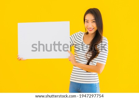 Portrait beautiful young asian woman show empty white billboard sign on yellow isolated background