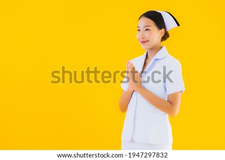 Portrait beautiful young asian thai nurse sawasdee or say hello in Thai on yellow isolated background