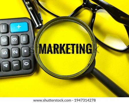 Selective focus of calculator,pen,glasses and magnifying glass with text MARKETING on yellow background.Business concept.