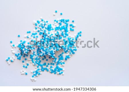 Six pointed star bakeware and blu white sprinkles on white background.