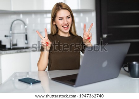 Young woman use laptop and showing peace sign