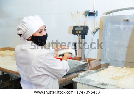 Young latin american woman working in bakery, preparing portioned pieces of dough for baking