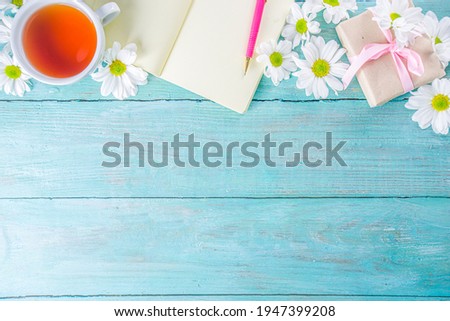 Cozy breakfast in spring or early autumn tea with bouquet of daisy flowers and note book. Copy space, top view flat lay