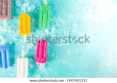Selection of bright multicolored ice cream popsicle. Various gelato, frozen lollypops - chocolate vanilla blueberry strawberry pistachio orange, with crushed ice on light blue sunny background Royalty-Free Stock Photo #1947401251