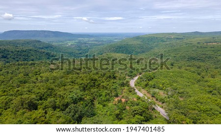 Aerial view from drone going through road on the mountain with green forest. View from the drone of the curve road. 