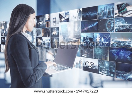 Data flow concept with businesswoman with laptop opposite media wall with video shots