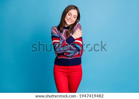 Portrait of pretty tender dreamy cheerful brown-haired girl hugging herself isolated over vibrant blue color background