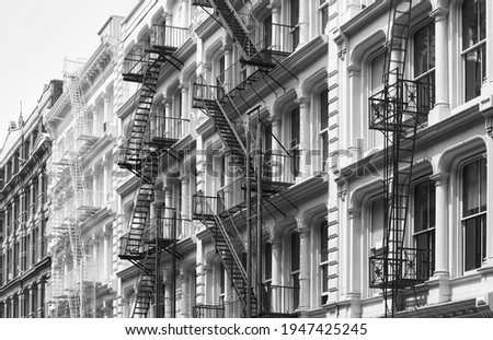Row of old building with iron fire escapes, black and white picture of New York cityscape, USA.