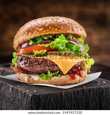 Delicious hamburger on a wooden table with a dark brown background behind. Fast food concept.