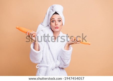 Photo of amazed astonished young lady hold bottles shampoo spa lotion isolated on pastel beige color background