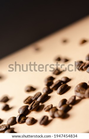 Coffee grain beige background top view. Textured background for the design. Brown roasted macro beans scattered on the table in natural sunlight. Full frame, copy space. Grains for making cappuccino