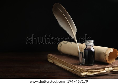 Feather pen, bottle of ink, old book and parchment scroll on wooden table. Space for text Royalty-Free Stock Photo #1947467179