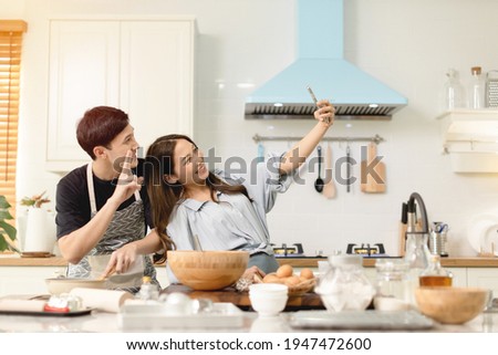 A couple uses their smart phone to take a picture while admiring his wife's cooking work With a happy face in an atmosphere of love