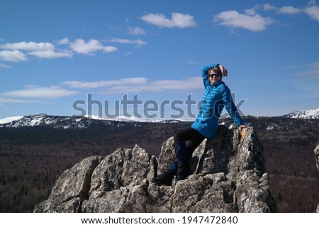 Sports, beautiful girl tourist against the background of a mountain landscape in the southern Urals. A slender cutie in a bright jacket on a hike in the mountains.