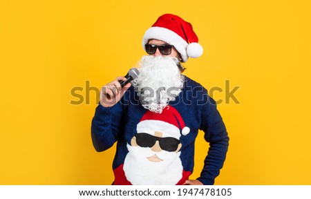 bearded santa man singing in microphone in hat smiling while prepare for celebrating happy new year party and christmas holiday in winter going to have xmas gifts, karaoke party