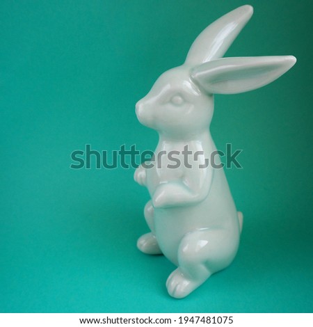 close-up ceramic figurine of a blue Easter bunny on a turquoise background side view