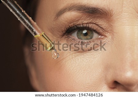 Closeup of female eye and dropper with rejuvenating serum Royalty-Free Stock Photo #1947484126