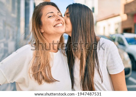 Beautiful hispanic mother and daughter kissing at the city.