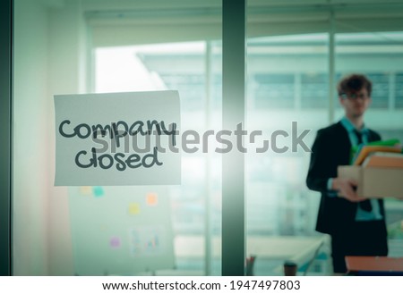 Company closed on windows of an empty office with business man packing beloning walking out of business by economic recession concept. Royalty-Free Stock Photo #1947497803