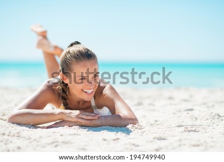Portrait of smiling young woman laying on beach and looking on copy space Royalty-Free Stock Photo #194749940