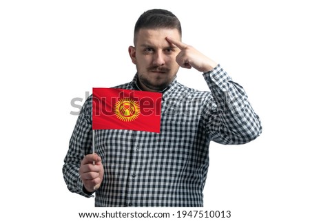 White guy holding a flag of Kyrgyzstan and a finger touches the temple on the head isolated on a white background.