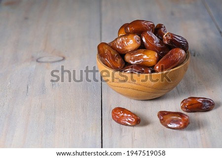 Closeup delicious Kurma Tunisia or sweet dried date palm fruits on wooden bowl. Much sought after during Ramadan to break the fast.  Royalty-Free Stock Photo #1947519058