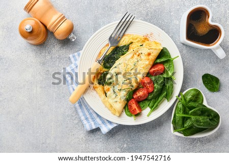 Omelet or omelette with spinach, cherry tomato and pepper seasoning on a white plate, on light grey background. Healthy breakfast concept. Top view.