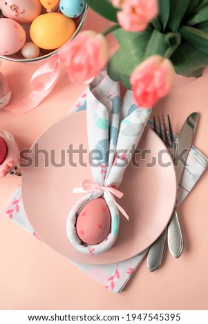 Festive Easter table setting with napkin Easter Bunny on pink table. Easter celebration concept. Soft focus. Top view