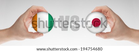 Man's hands holding styrofoam balls with Cote D Ivoire and Japan flag against the white background.