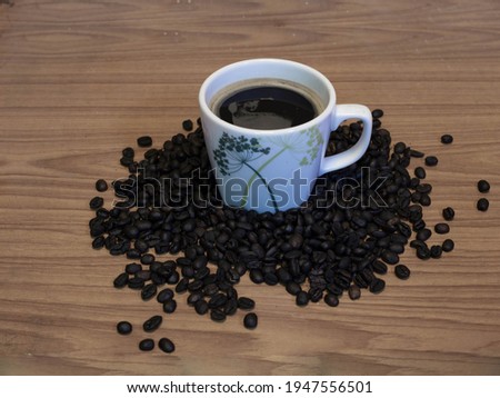 A cup of coffee with coffee beans on wooden table.