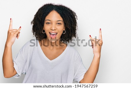 Young african american girl wearing casual clothes shouting with crazy expression doing rock symbol with hands up. music star. heavy concept. 