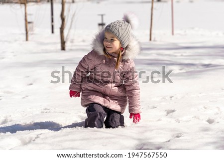 child girl fell into a snowdrift knee-deep. large snow level