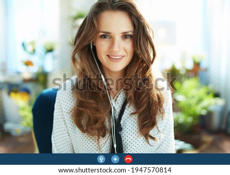 Green Home. happy trendy housewife with long wavy hair in the modern house in sunny day having online meeting.