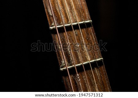 Acoustic guitar fretboard with rusty strings and dramatic light on a black background  Royalty-Free Stock Photo #1947571312