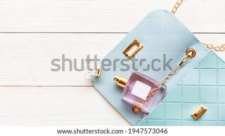Fashion blue bag woman accessories set. Trendy blue fashion with perfume on wood white background. Fashion Concept.