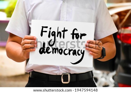 Protester holds wordcard 'Fight for democracy‘, concept for calling all people to be protesters and fight for democracy from revolutions, coups, and restrictions on freedom from the people. Royalty-Free Stock Photo #1947594148